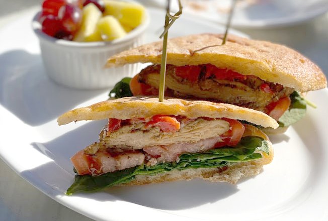 Grilled chicken panini sandwich with a side of fruit