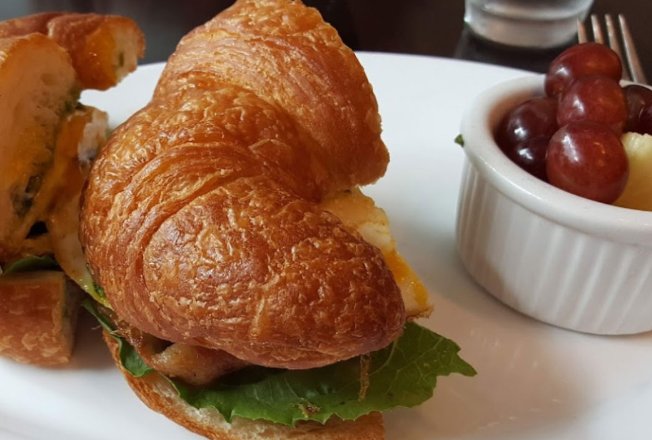 Croissant sandwich served with grapes and pineapple